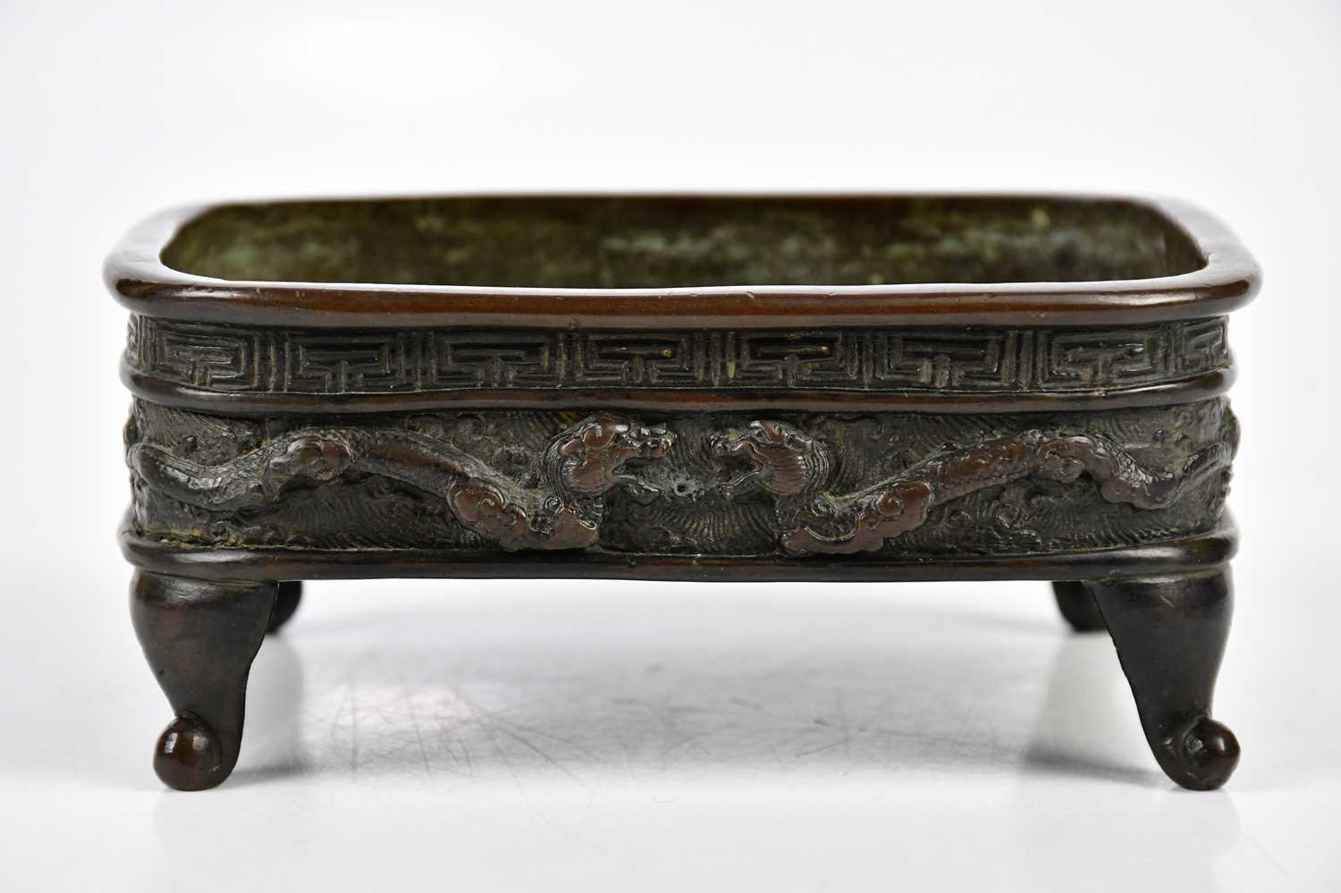 A late 19th century Japanese bronze bowl, with cast decoration of mythical beasts and Greek key