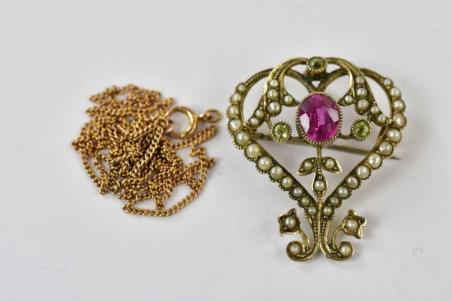 An Edwardian 9ct yellow gold seed pearl, peridot and pink sapphire brooch suspended on a 9ct gold