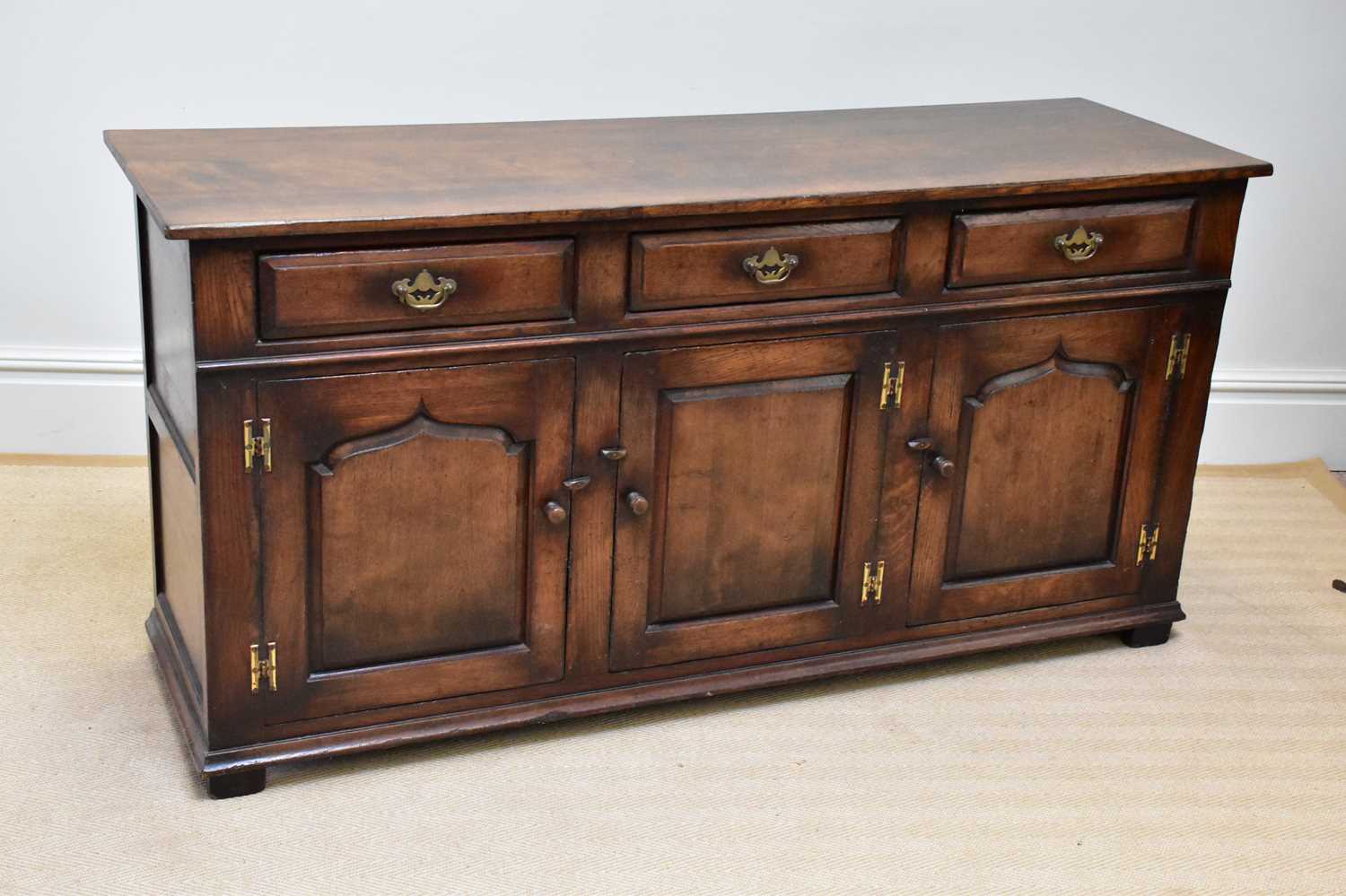 A reproduction oak dresser base with three drawers above three panelled cupboard doors on block