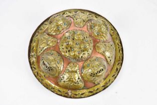 An Eastern copper and brass dahl type shield with stylised mask heads and turquoise set eyes,
