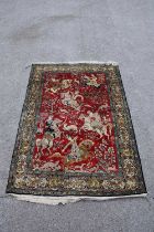 An Eastern style part silk rug, decorated with figures on horseback hunting, on a predominantly