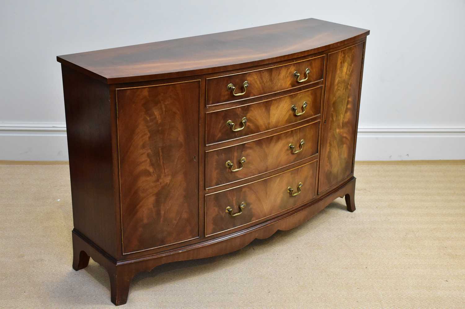 A reproduction mahogany bowfront sideboard with four drawers flanked by single panelled cupboard