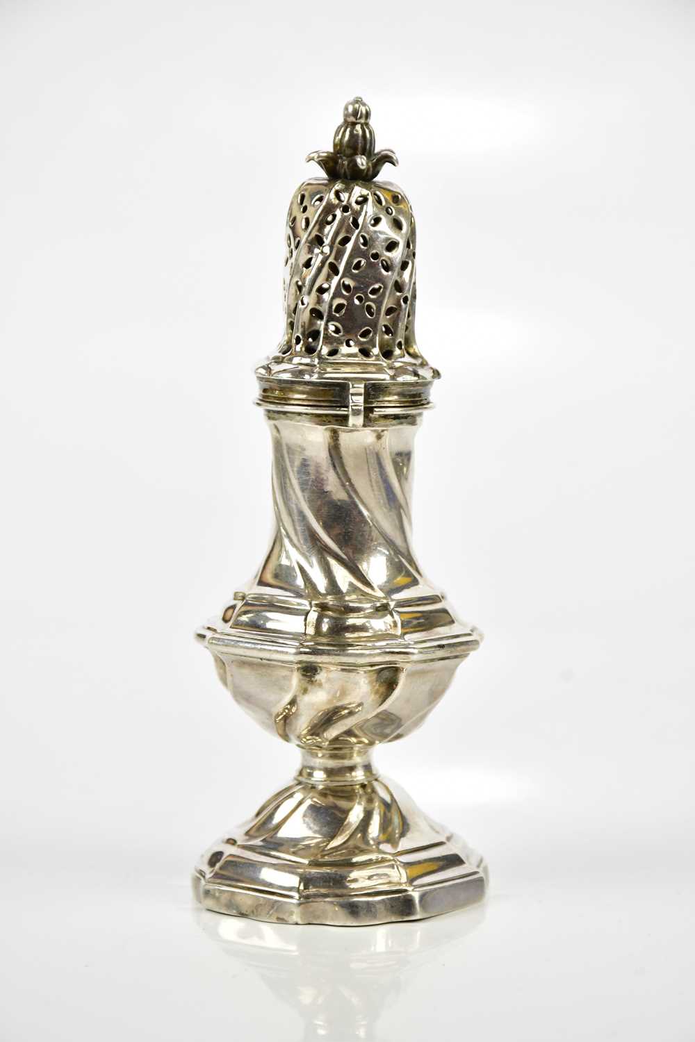 A Georgian white metal pepperette, with open pineapple finial above the wrythen body, indistinctly