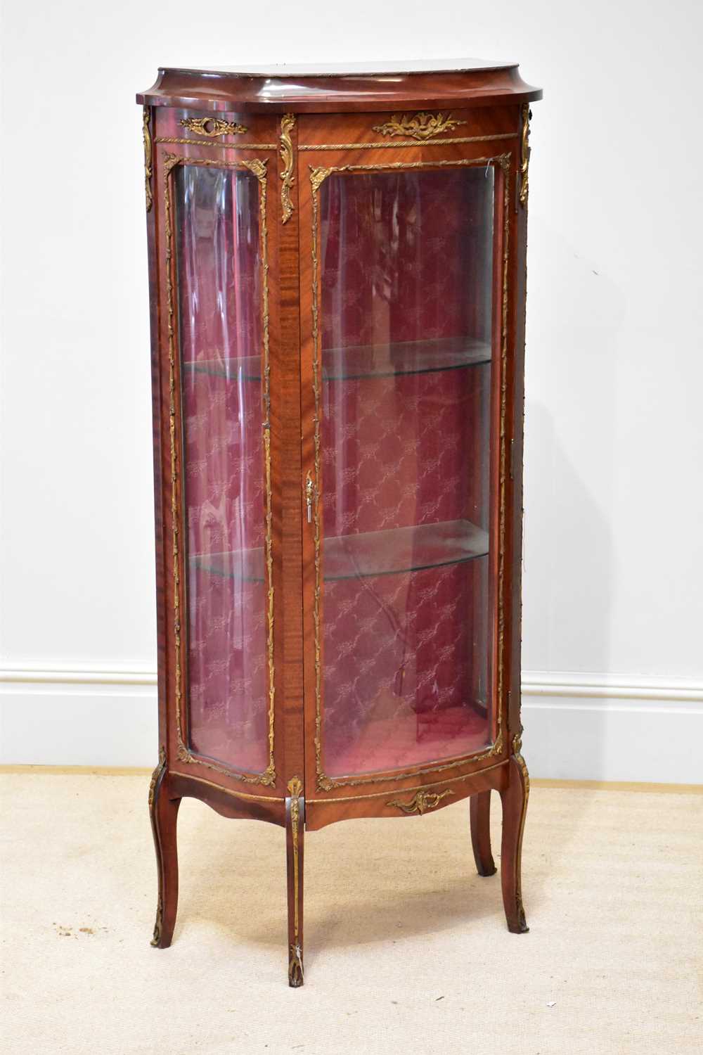 A reproduction kingwood bowfront vitrine with applied gilt metal detail, the glazed door enclosing