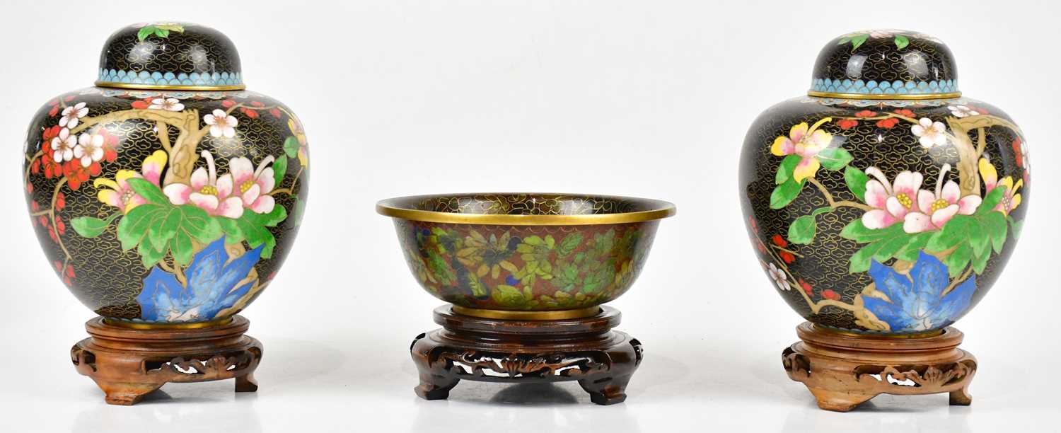 A pair of 20th century Chinese cloisonné ginger jars and covers, with prunus decoration, on wooden