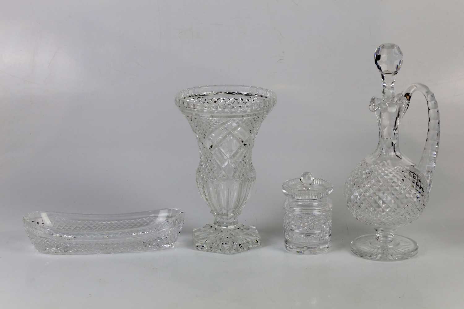 WATERFORD CRYSTAL; a group of four cut glass items comprising claret jug, vase, dish and lidded jar,