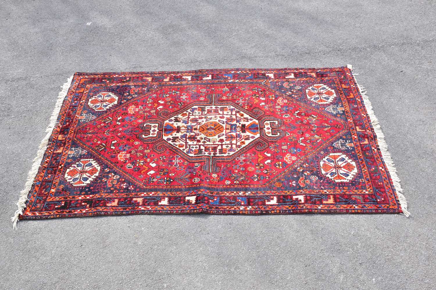 A red ground wool rug with central geometric pattern, 209 x 138cm.