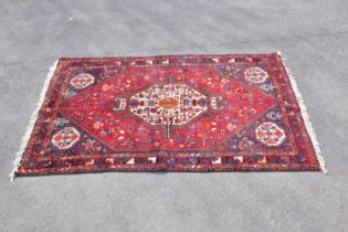 A red ground wool rug with central geometric pattern, 209 x 138cm.