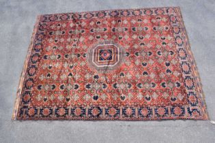 An orange ground wool carpet with central geometric pattern, 287 x 215cm.