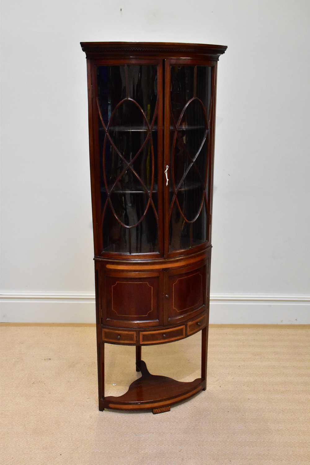 An Edwardian satinwood inlaid mahogany bowfront corner display cabinet, with two astragal glazed