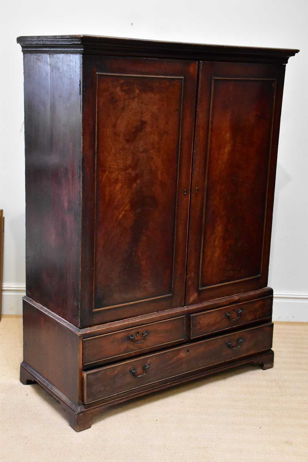 A George III mahogany linen press, with two doors above three drawers, on bracket feet, converted