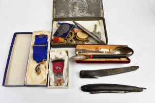 A circa 1900 Queen Victoria South Africa tin, assorted cap badges, cased cut throat razors,