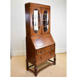 An early 20th century oak bureau bookcase, with two leaded glazed doors above fall front and two