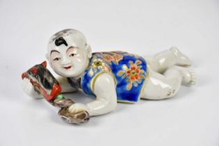 An early 20th century Chinese ceramic recumbent boy, 21cm. Condition Report: Minor crazing, paint