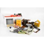 A mixed collection of cameras and camera accessories including photographic paper, a Kodak