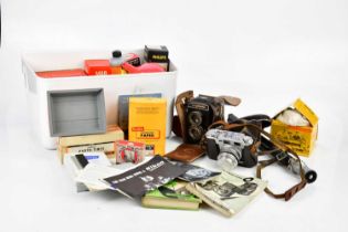 A mixed collection of cameras and camera accessories including photographic paper, a Kodak