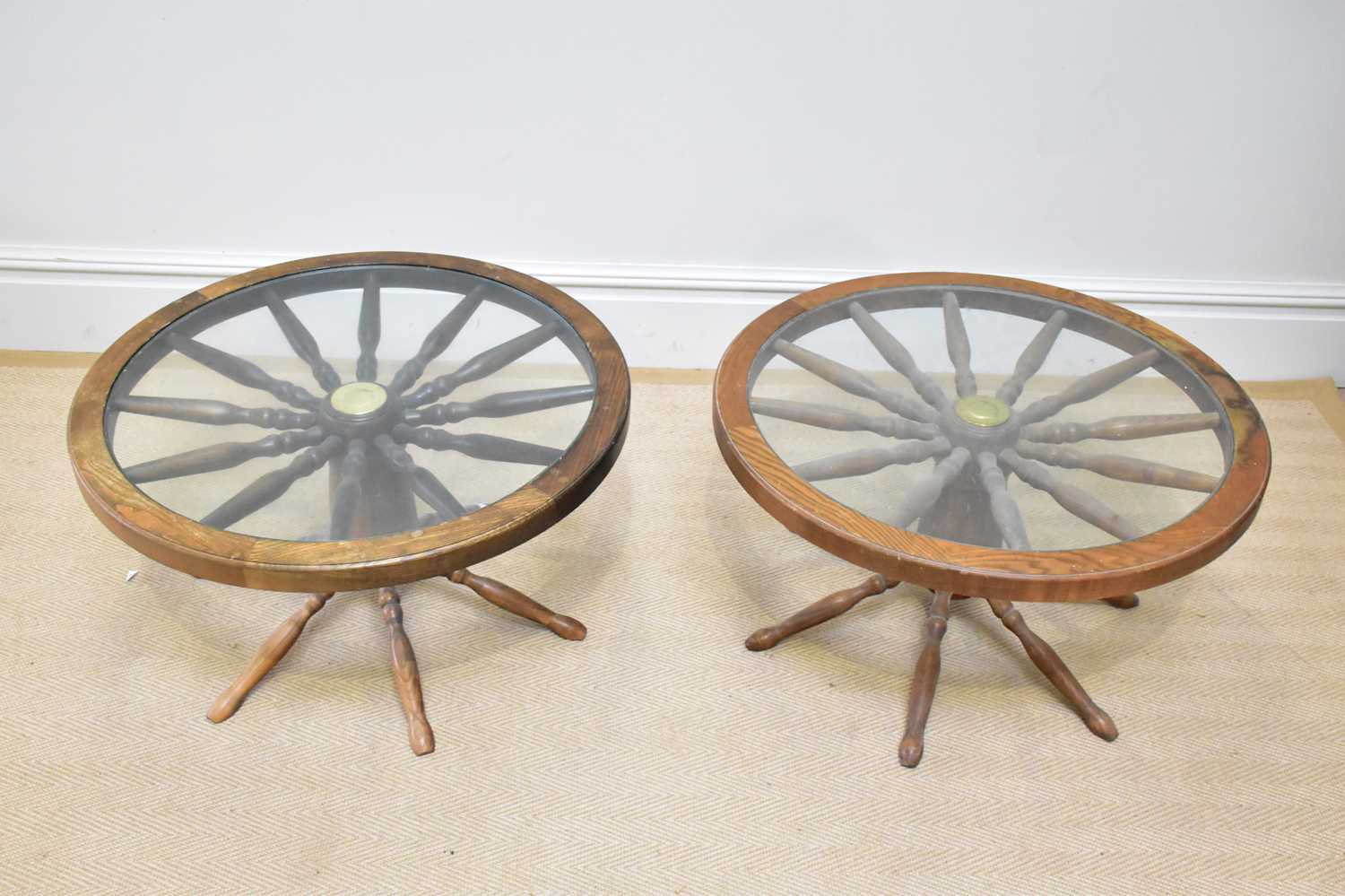 A pair of modern oak cartwheel coffee tables with glass tops, diameter 74cm.