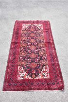 A red ground wool carpet with geometric pattern to the centre, 200 x 100cm.