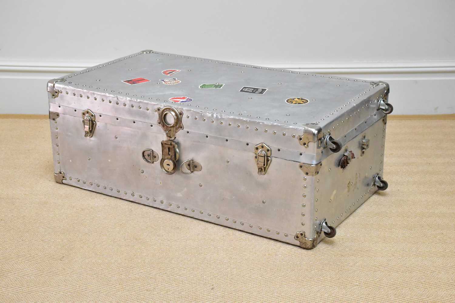 A silvered metal trunk with studded detail and applied vintage labels including 'Munson Steamship