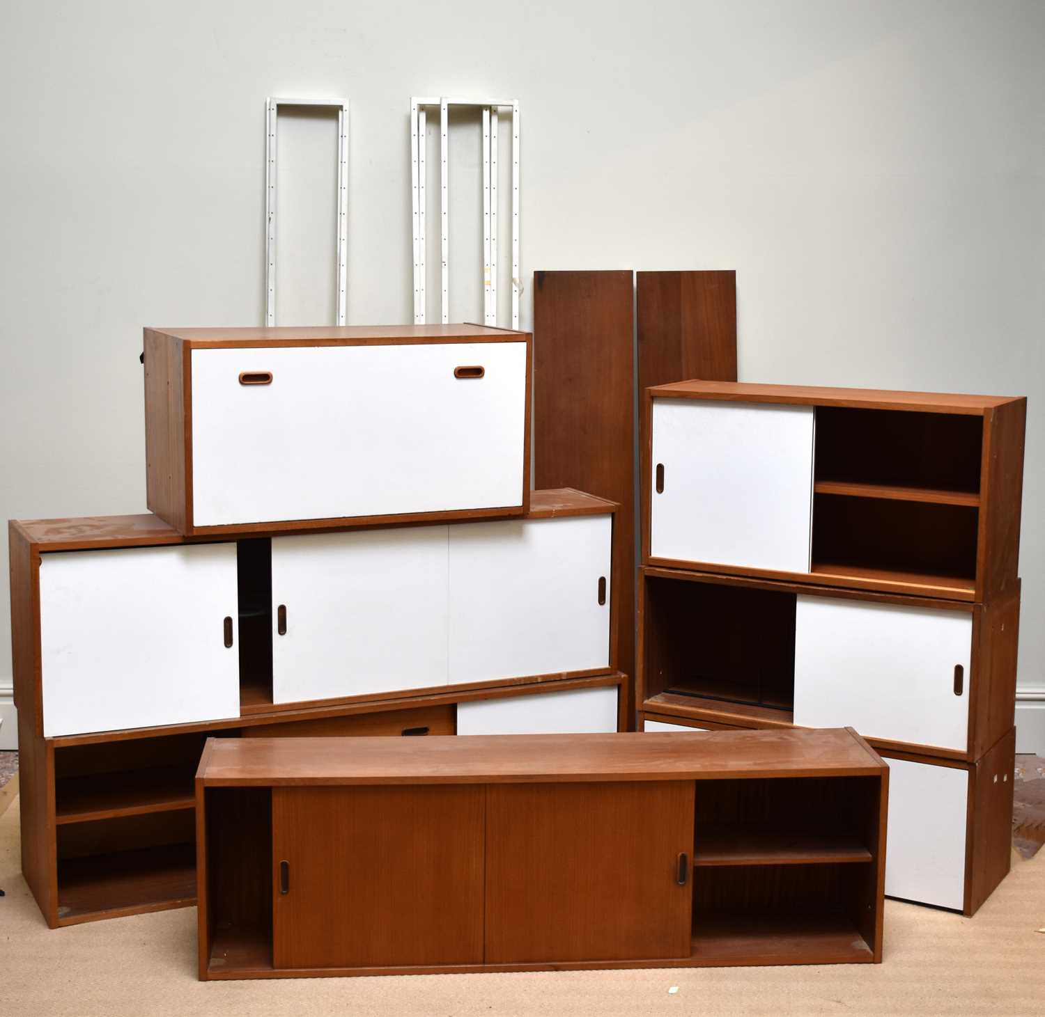 A mid century teak Ladderax type system, comprising seven units, two shelves and white metal