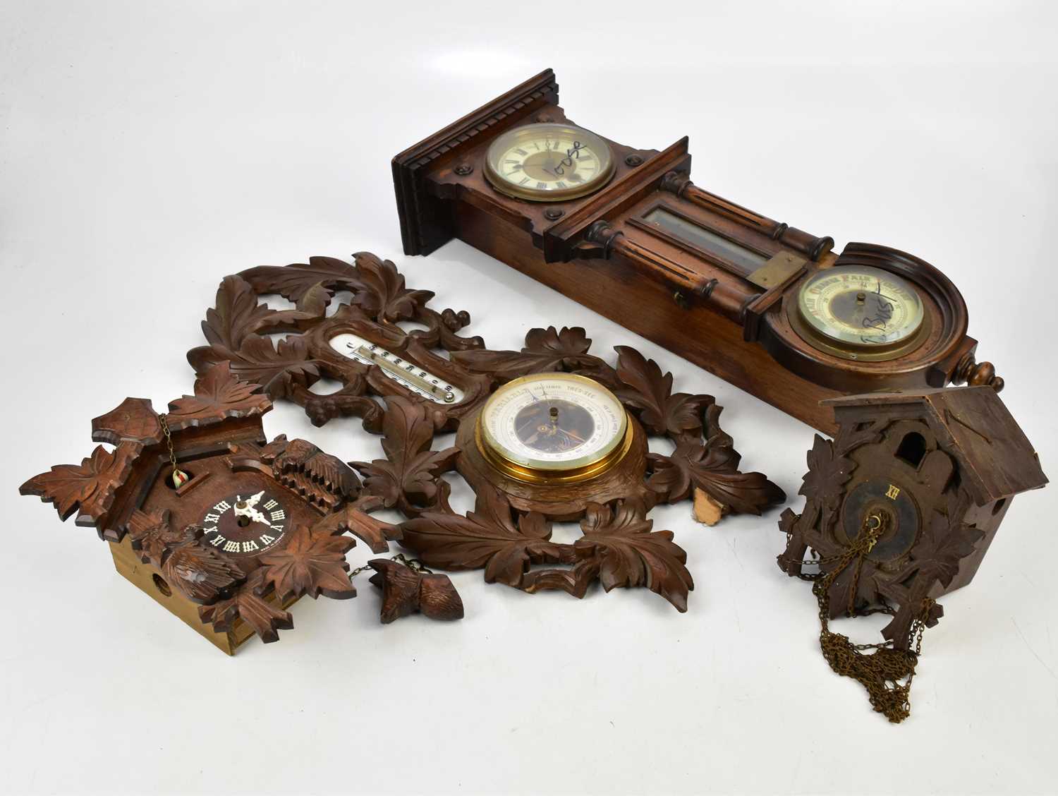 A Black Forest carved wood combination barometer and therometer, length 55cm, with two cuckoo clocks