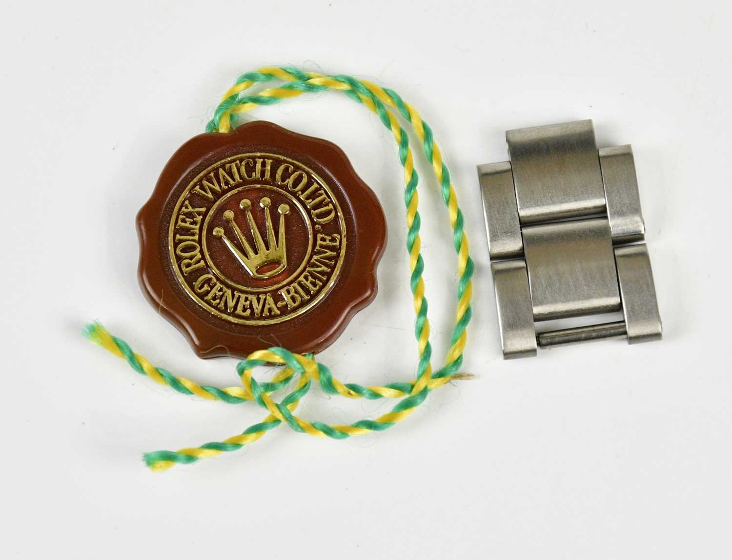 Two stainless steel links purportedly from a Rolex Explorer II, with tie-on tag.