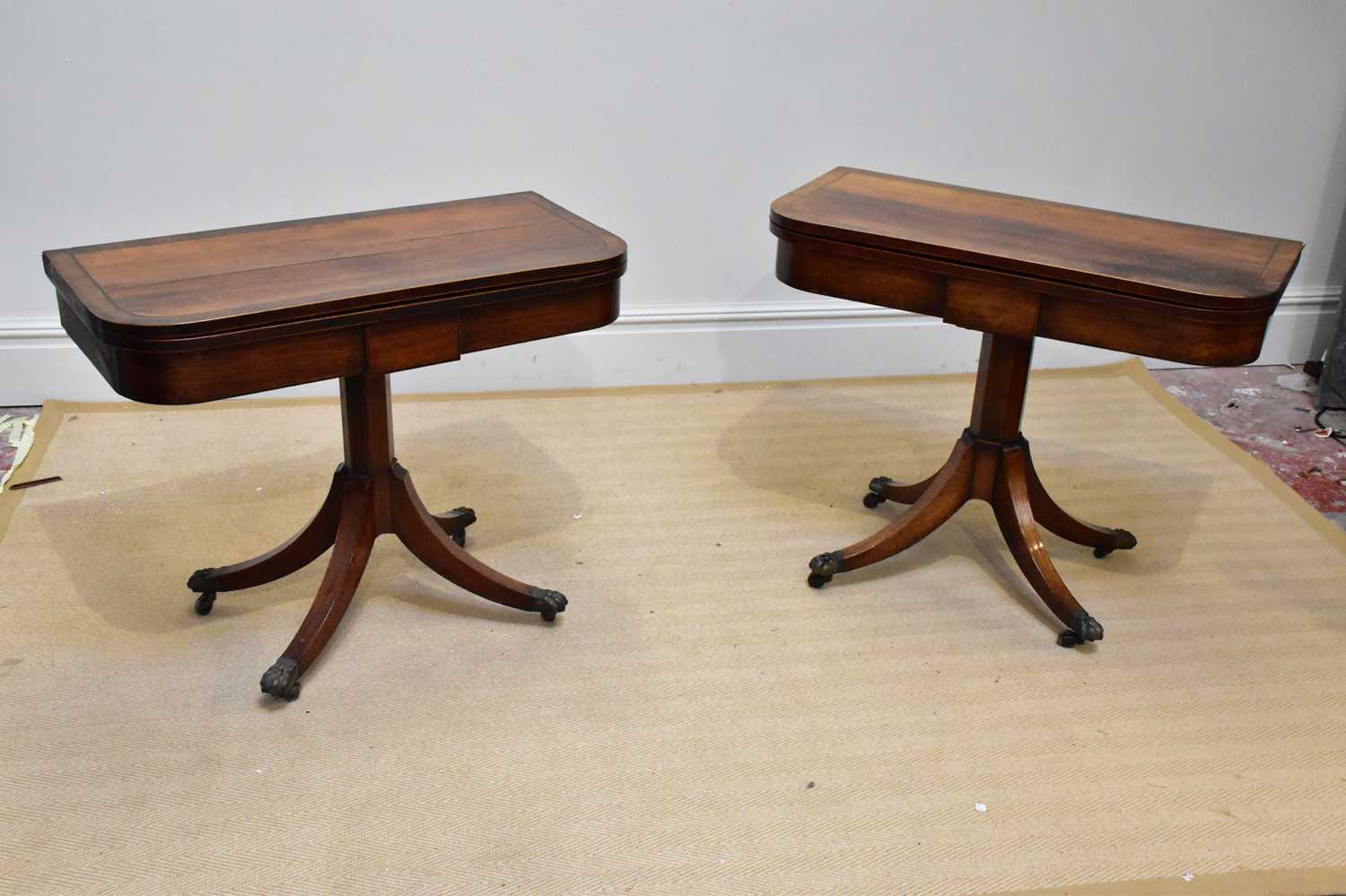 A near pair of Regency rosewood card tables, each with a swivel top on an octagonal column and