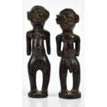 A pair of carved hardwood tribal fertility figures, possibly West African, modelled as a male and