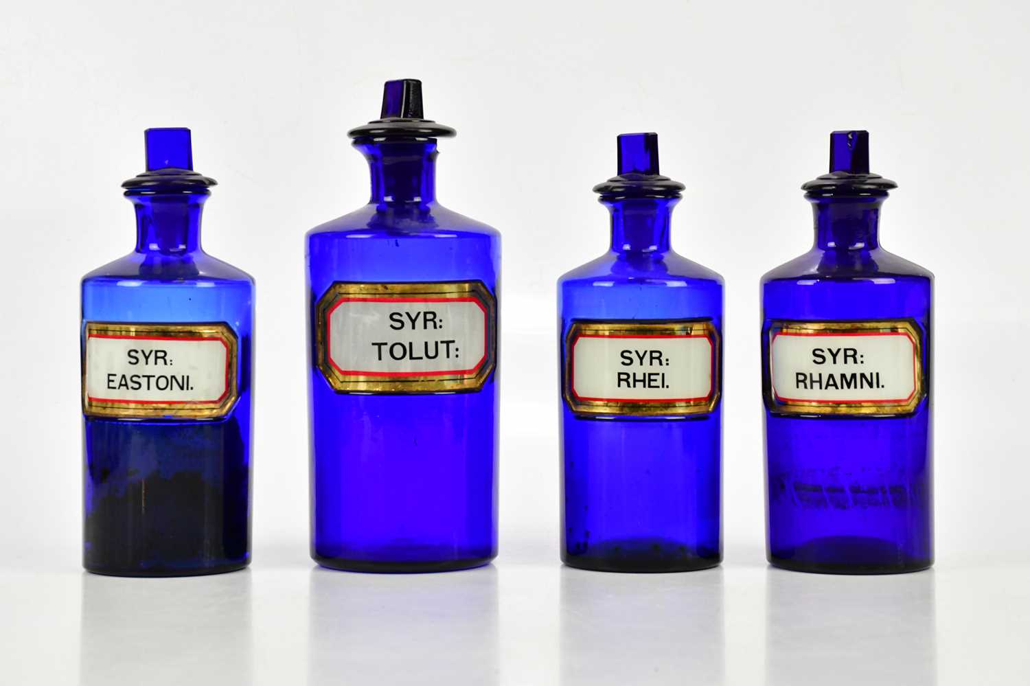 Four 19th century blue glass pharmacy bottles with labels and dummy stoppers, height of largest