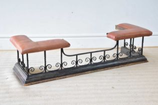A wrought iron club fender with scrolling decoration and leather top, length 153cm.