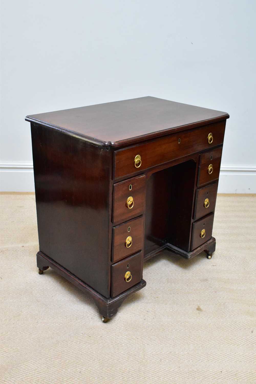 A George III mahogany kneehole desk, the seven drawers with later handles around a central