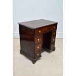 A George III mahogany kneehole desk, the seven drawers with later handles around a central