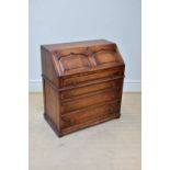 A reproduction oak bureau, the fall front with internal tooled leather, enclosing an assortment of