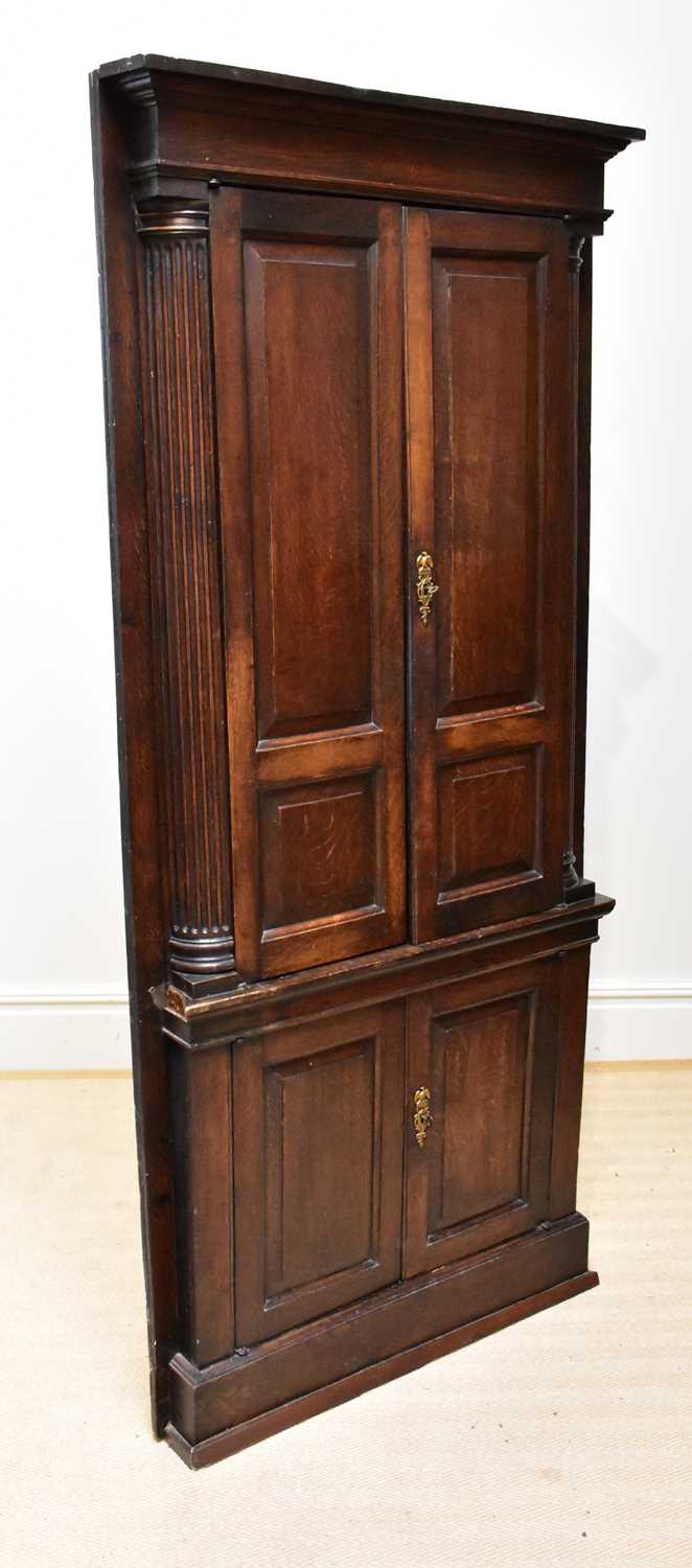 A George III oak corner cupboard, with two panelled doors flanked by fluted pilasters, above two