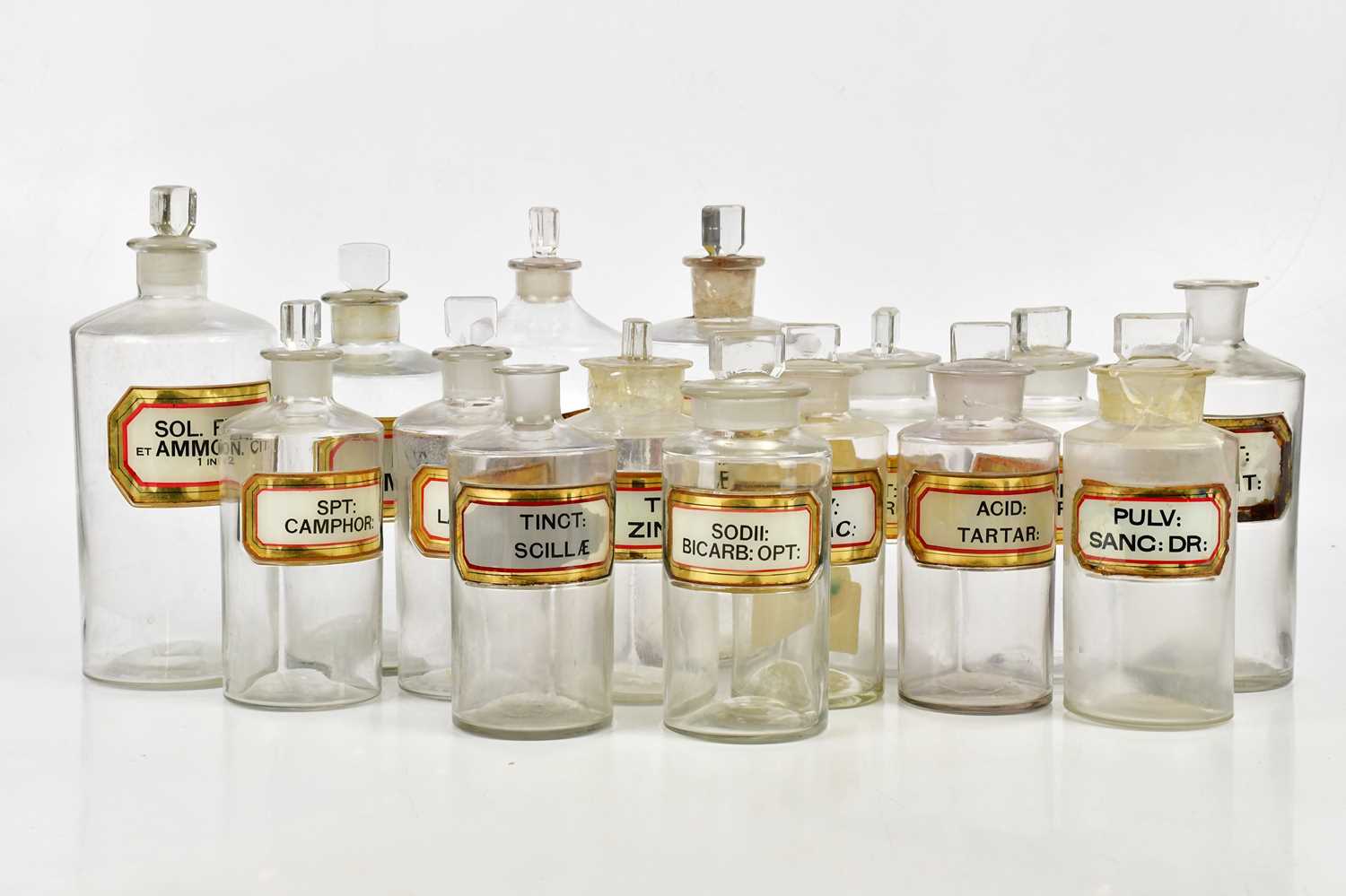 A collection of Victorian clear glass apothecary bottles predominantly with glass labels, various