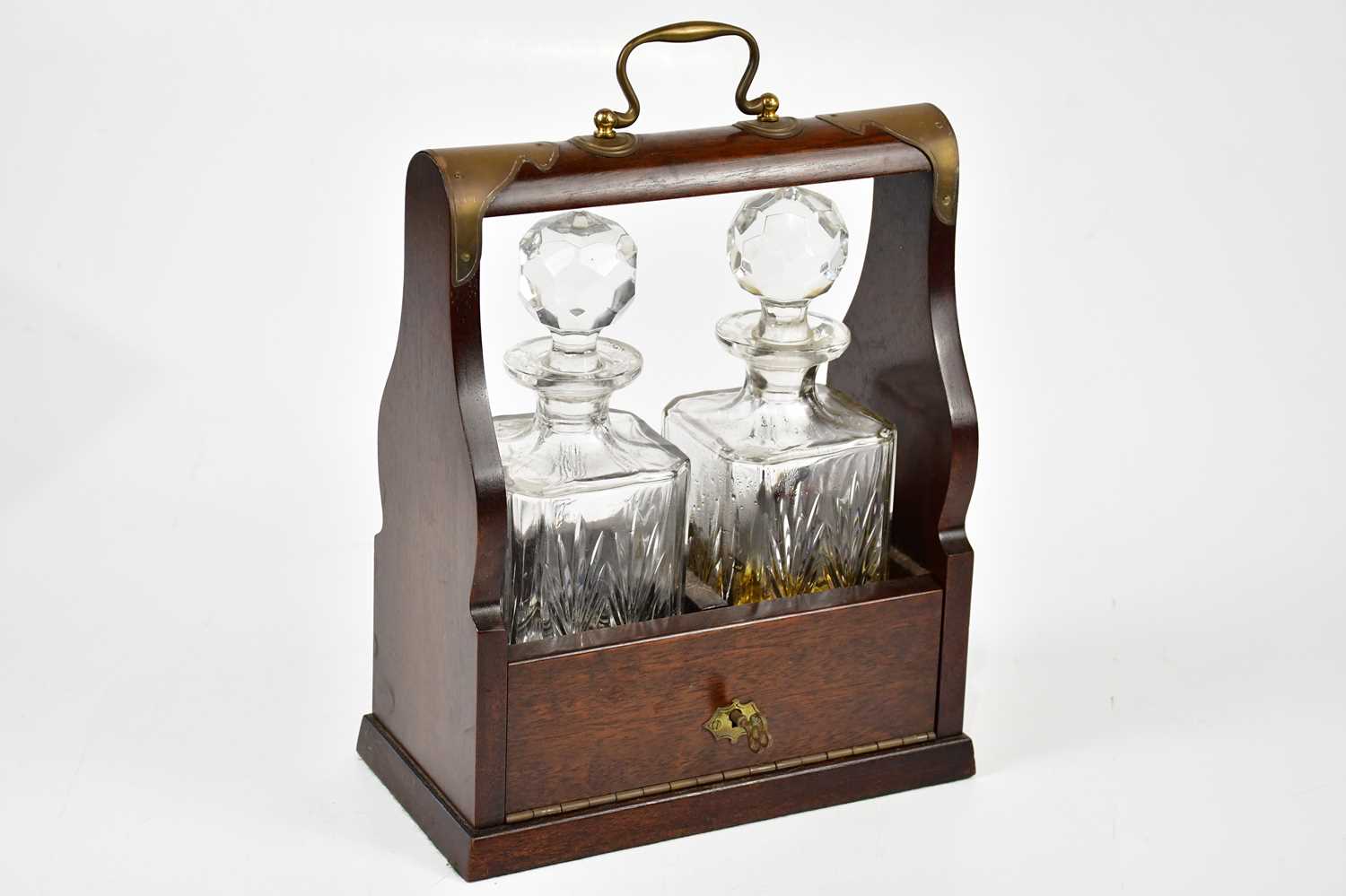 A modern brass bound mahogany cased tantalus housing two cut glass decanters.