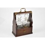 A modern brass bound mahogany cased tantalus housing two cut glass decanters.