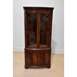 A reproduction mahogany bowfronted corner cupboard with moulded cornice above two astragal glazed