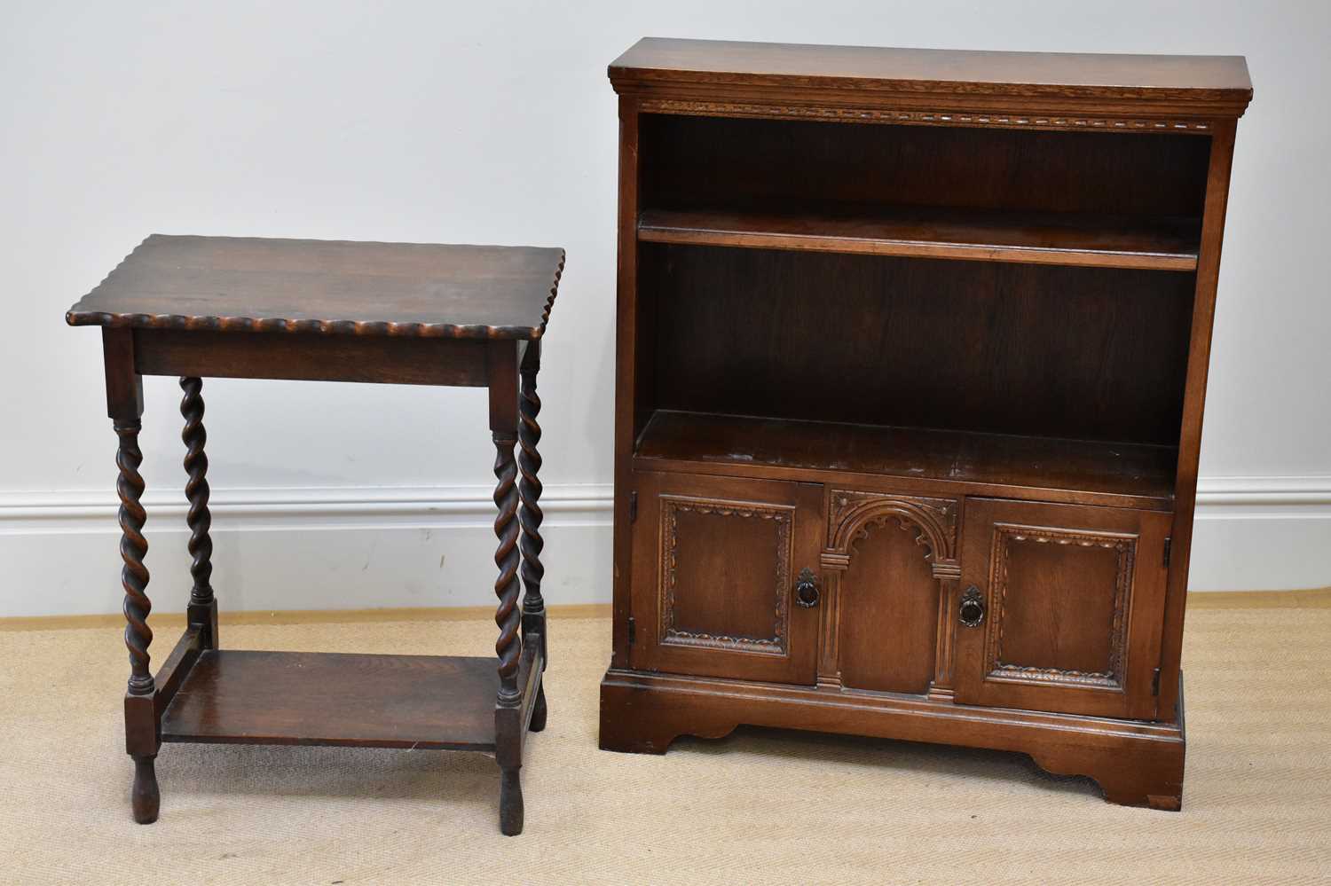 A reproduction oak freestanding bookcase with a fixed shelf above two panelled cupboard doors, width