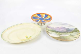 CLARICE CLIFF; a cake stand and platter, together with a hand painted wall charger, largest 30cm.