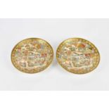 A pair of Japanese Meiji period Satsuma plates, each decorated with figures, open fans and landscape