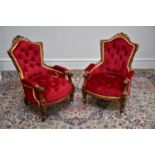 A pair of Victorian carved walnut framed salon chairs upholstered in a red material (2).