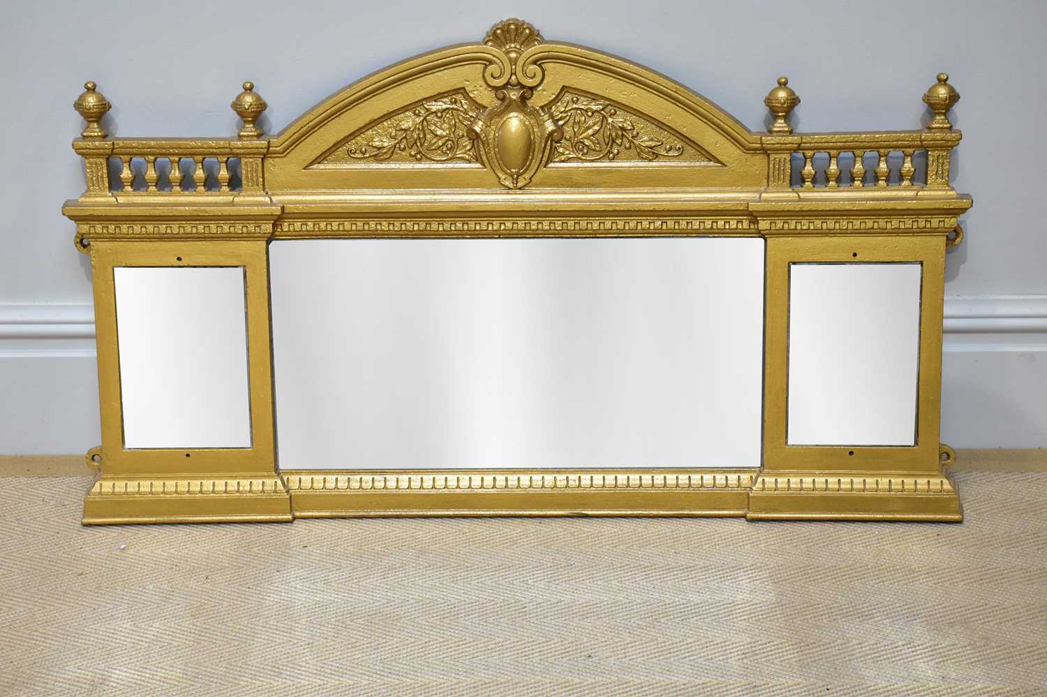 A gold painted cast iron overmantel mirror, with three bevelled plates, height 62cm, width 110cm.