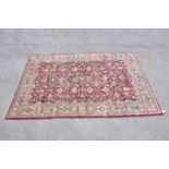 A red ground wool carpet with floral geometric central design, 230 x 157cm.