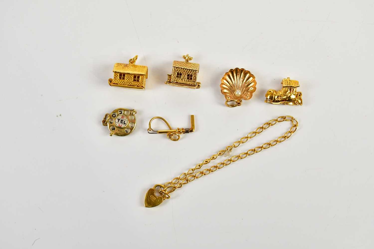 A collection of six 9ct gold charms including a riding crop, cottage, telephone dial, also a 9ct