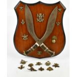 Two Gurka kukri knives mounted onto a shield shaped back plate with badge for 18th Cavalry and