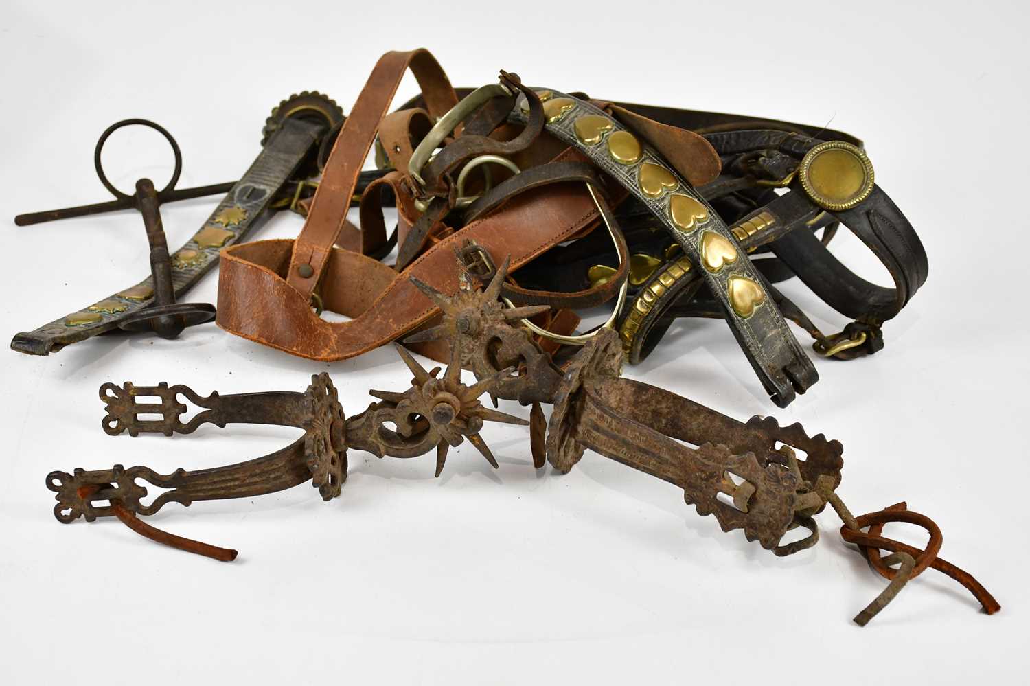 A pair of cast metal boot spurs and a collection of horse brasses.