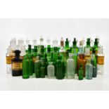 A collection of pharmaceutical glass bottles, with etched and paper labels, including green