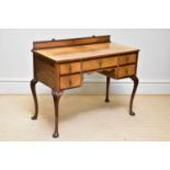 A 1950s walnut kneehole dressing table with an arrangement of five drawers on carved cabriole