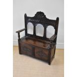An early 20th century carved oak hall settle, with raised back and hinged seat, width 107cm,